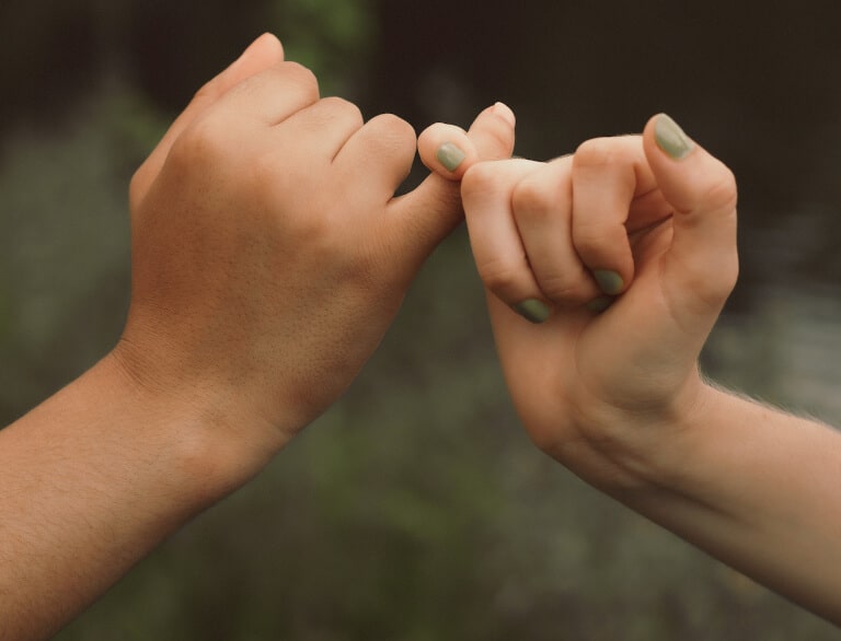 Händerna tillhörande två vänner som avger ett löfte till varandra