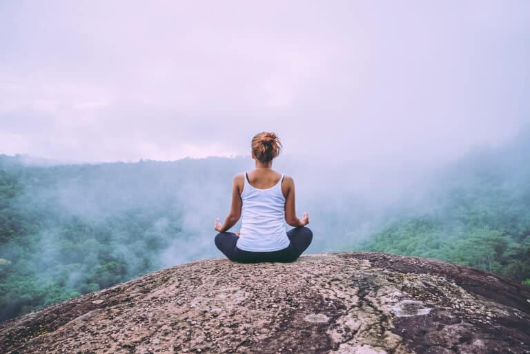 Kvinna som sitter på en kulle och mediterar